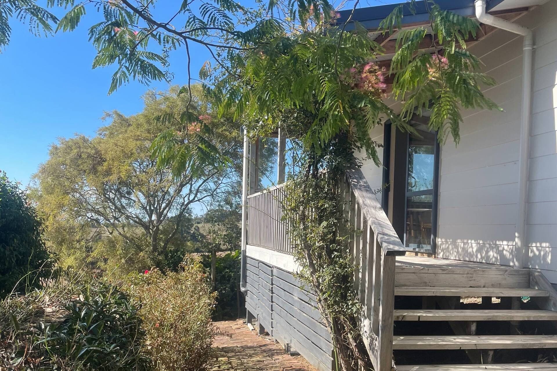The cottage exterior with a flowering tree over the front steps