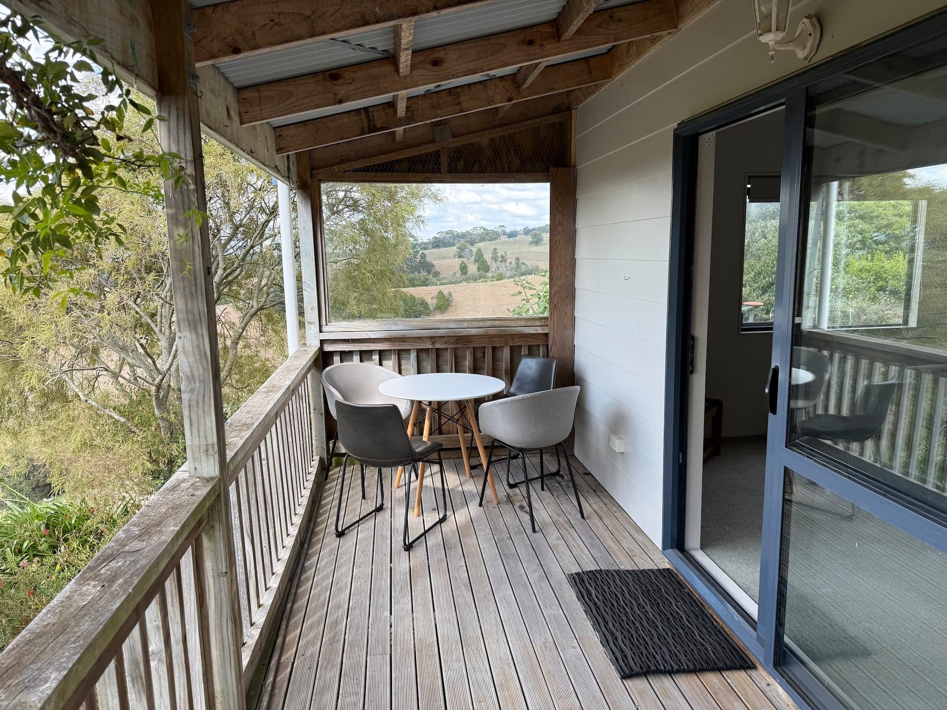 Covered balcony with a table and chairs looking out over rolling Waikato farmland